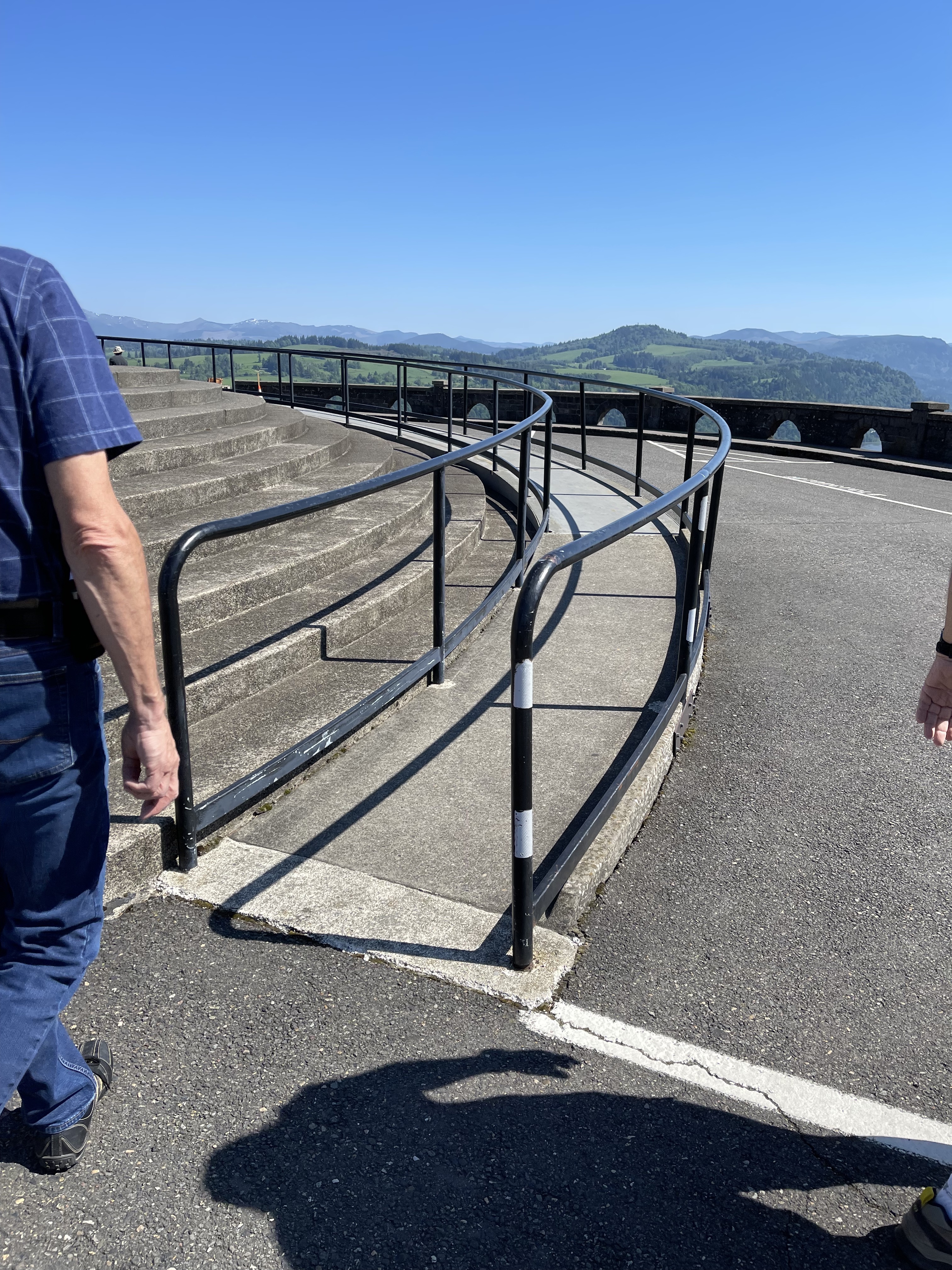 Large ramp winds around building to entrance, and has handrails on both sides.