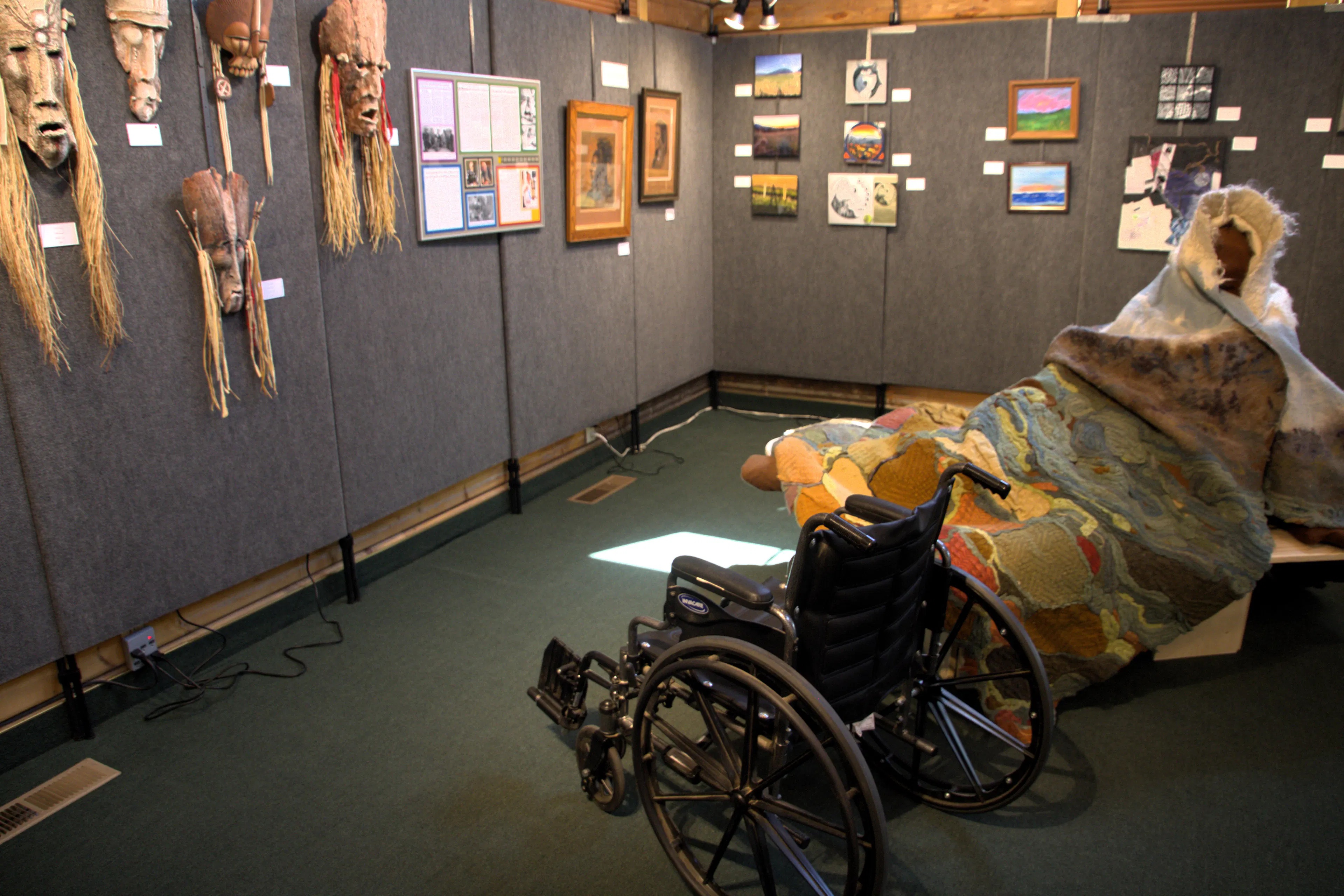 Art display of african masks. wheelchair in the shot to show room