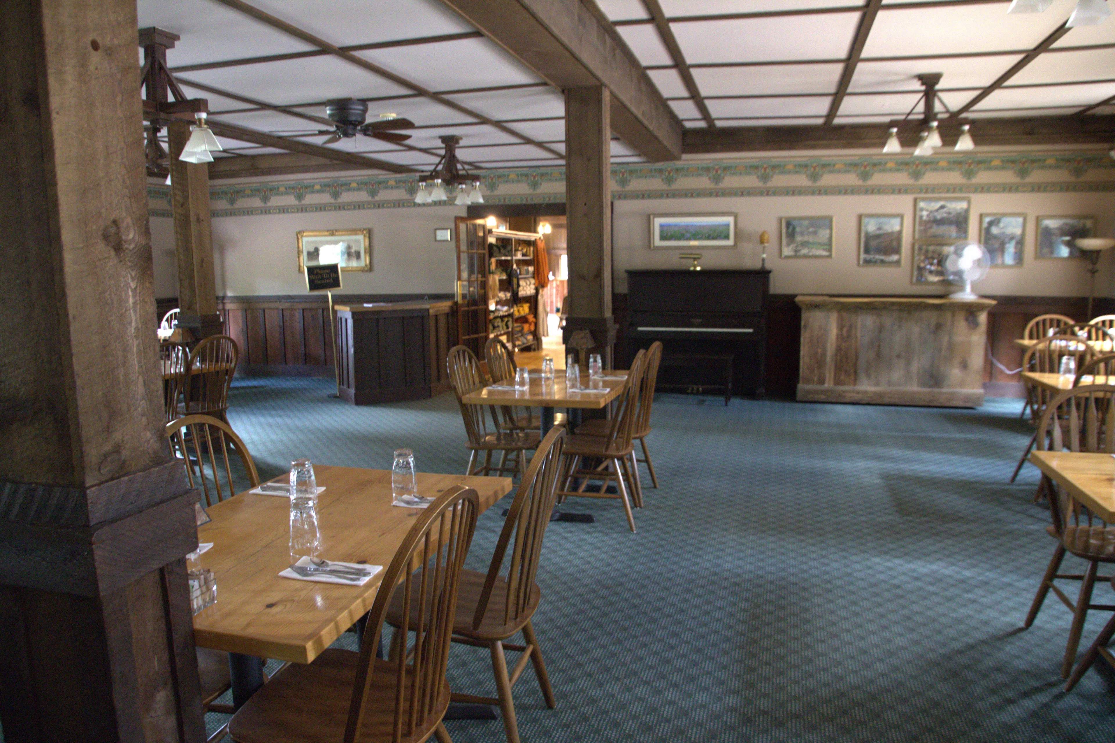 Restaurant interior. Tables and chairs throughout. Wooden chairs, no armrests. Chairs could be moved to accomodate wheelchair.