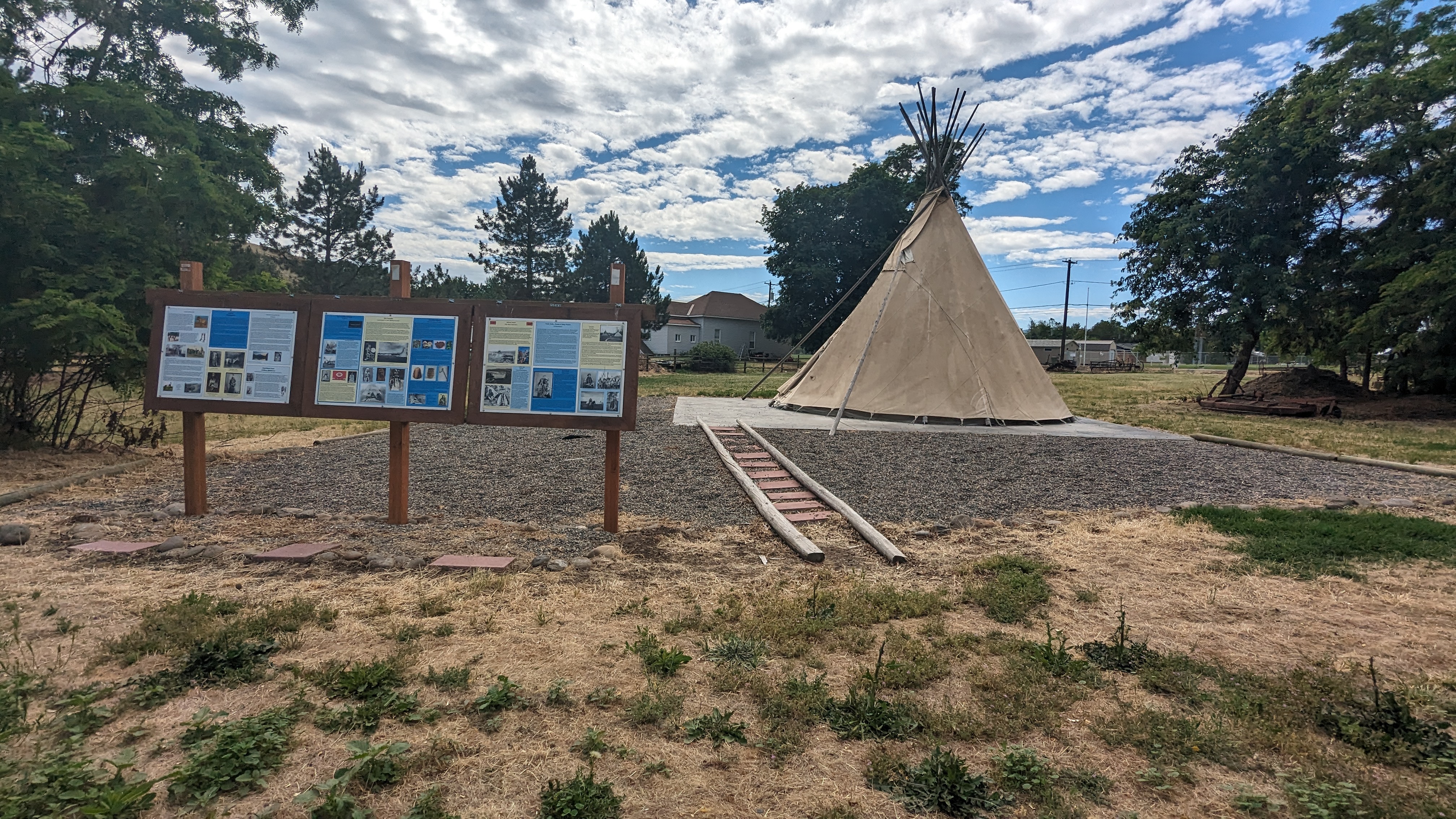 Path to Tipi is spaced out pavers surrounded by gravel and lined with narrow logs.