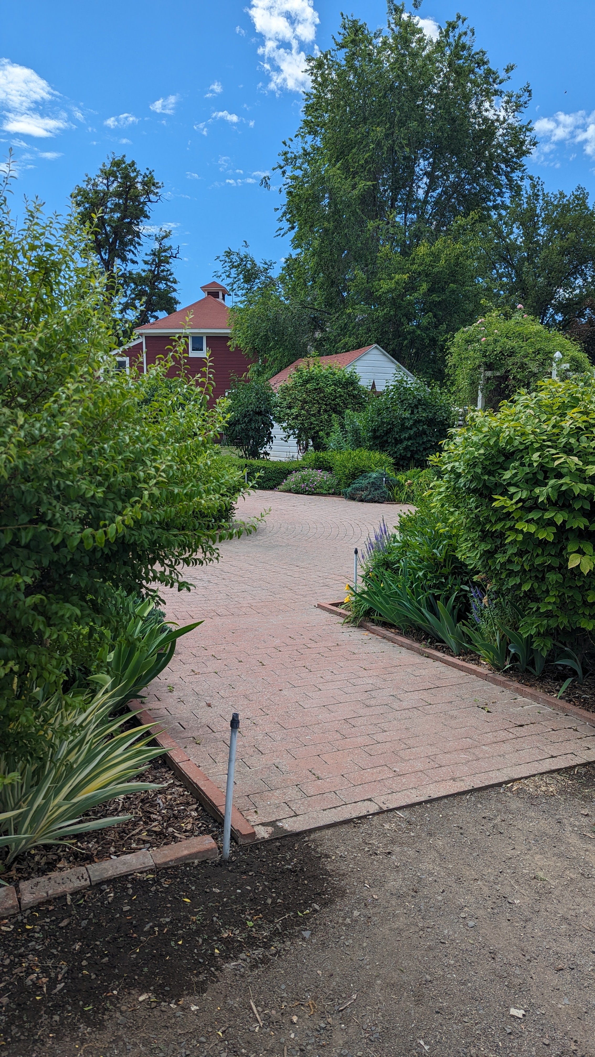 Brick path from gravel lot to garden area with seating.