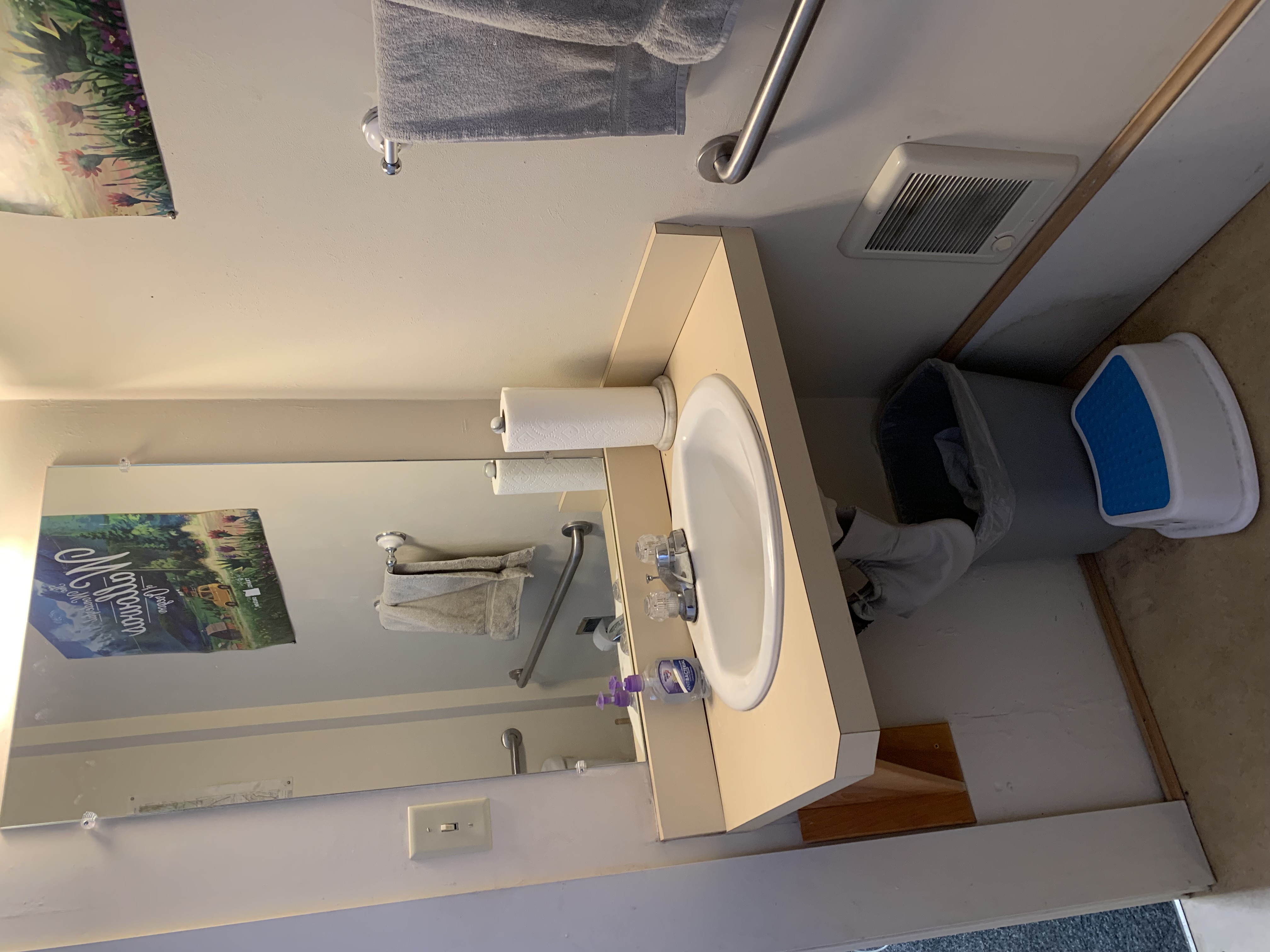 Facing the sink, with the toilet behind the camera. The bathroom door is to the left.
