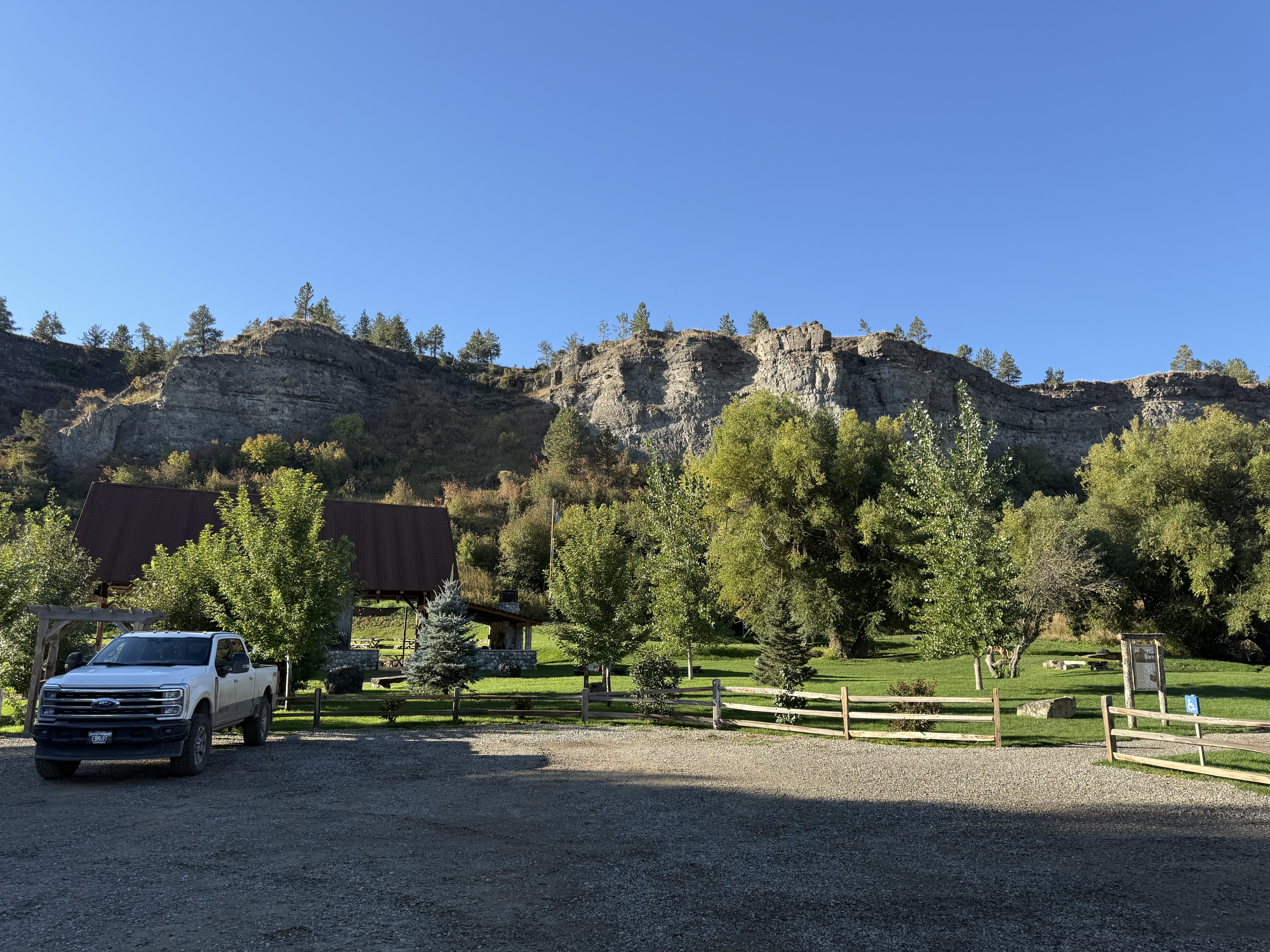 large, level packed gravel parking lot, accessible spaces marked on the right side.