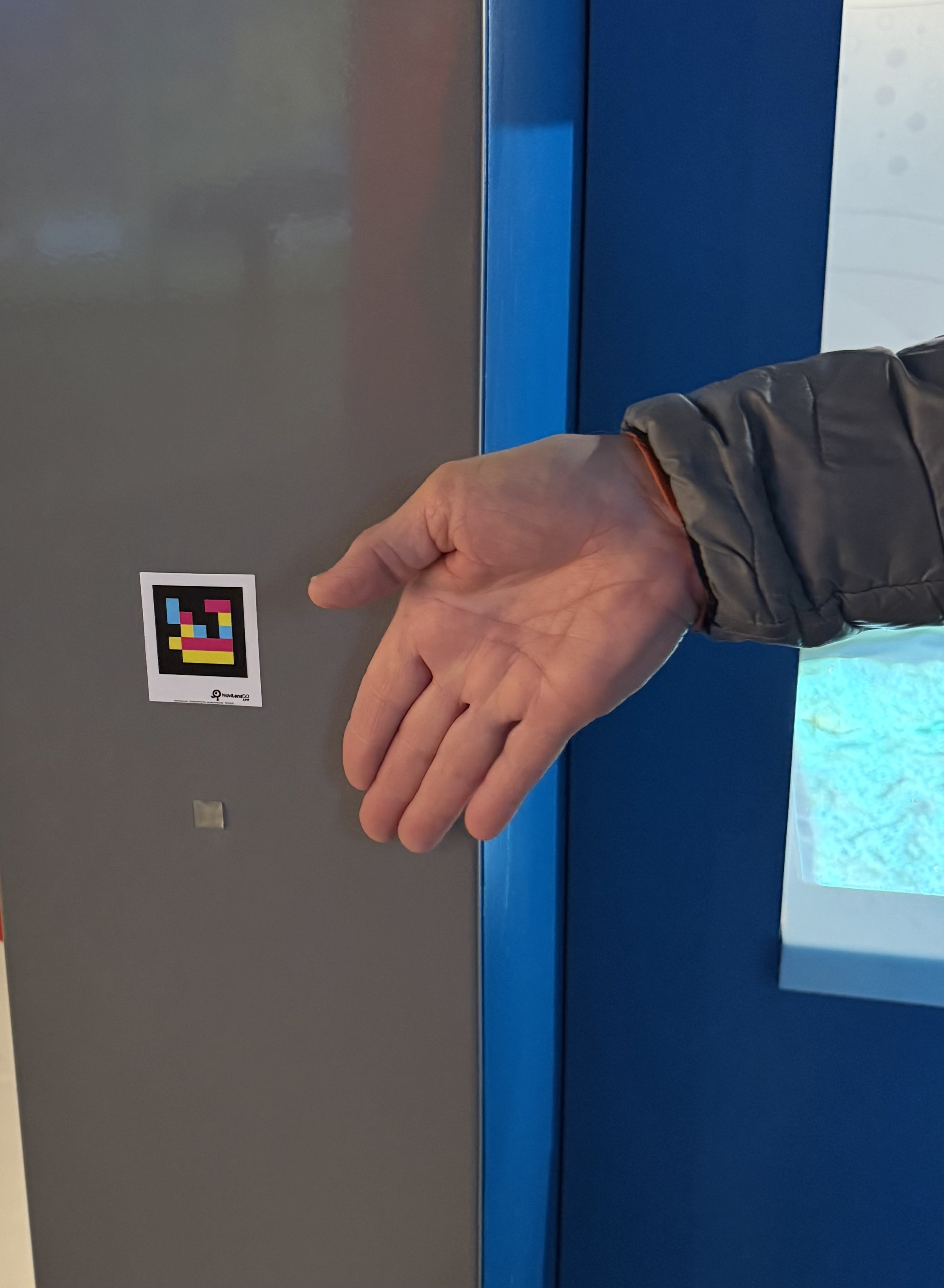 Navilens sticker about the size of a stamp. Located throughout the exhibits. The Navilens app will scan and read the text to you about the exhibits